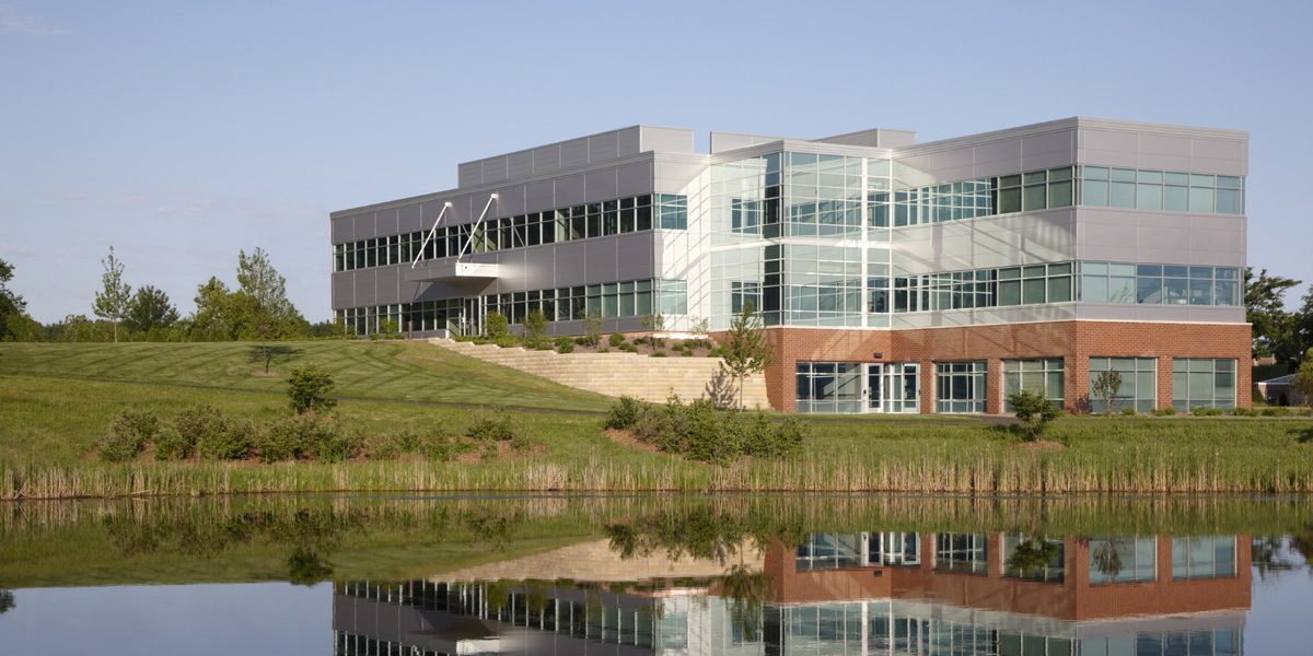 Multi-story office building surrounded by pond and open grassland